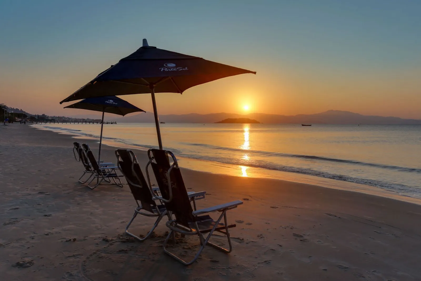 Pôr do sol com guarda-sol na praia do hotel