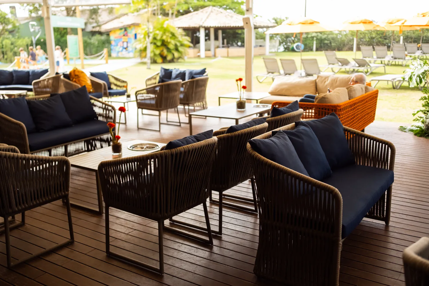 Lounge de deck com poltronas e almofadas azuis, aberto para o gramado