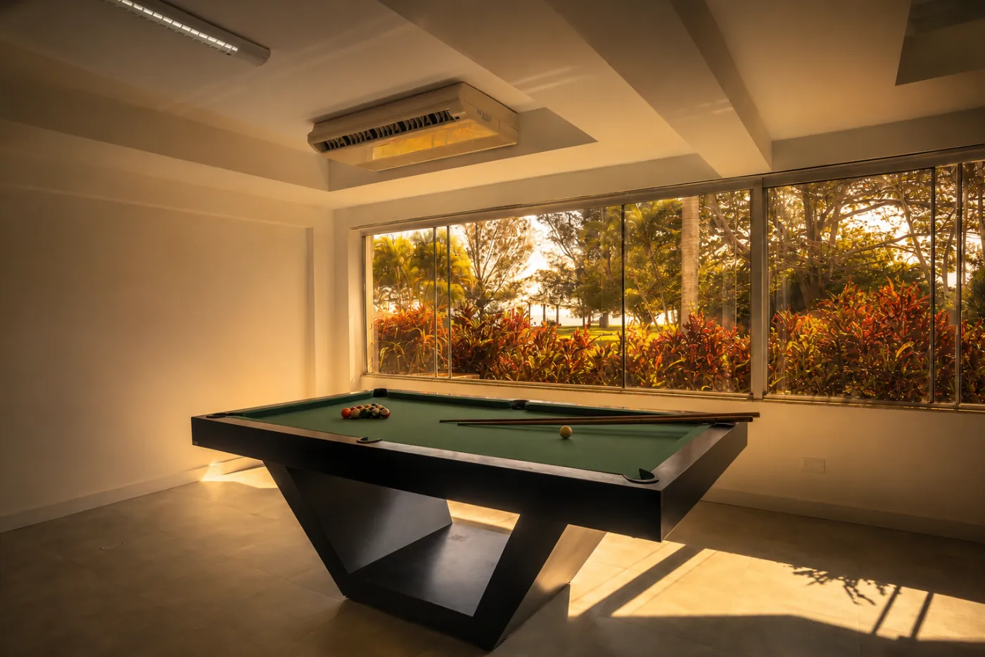 Mesa de sinuca em salão climatizado com janela para o jardim