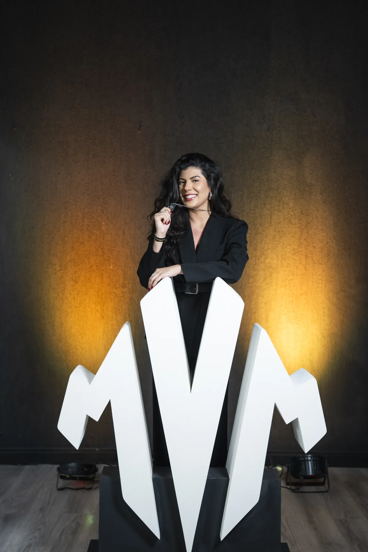 Membra da comunidade MVM apoiada no letreiro do MVM na primeira edição do Legacy